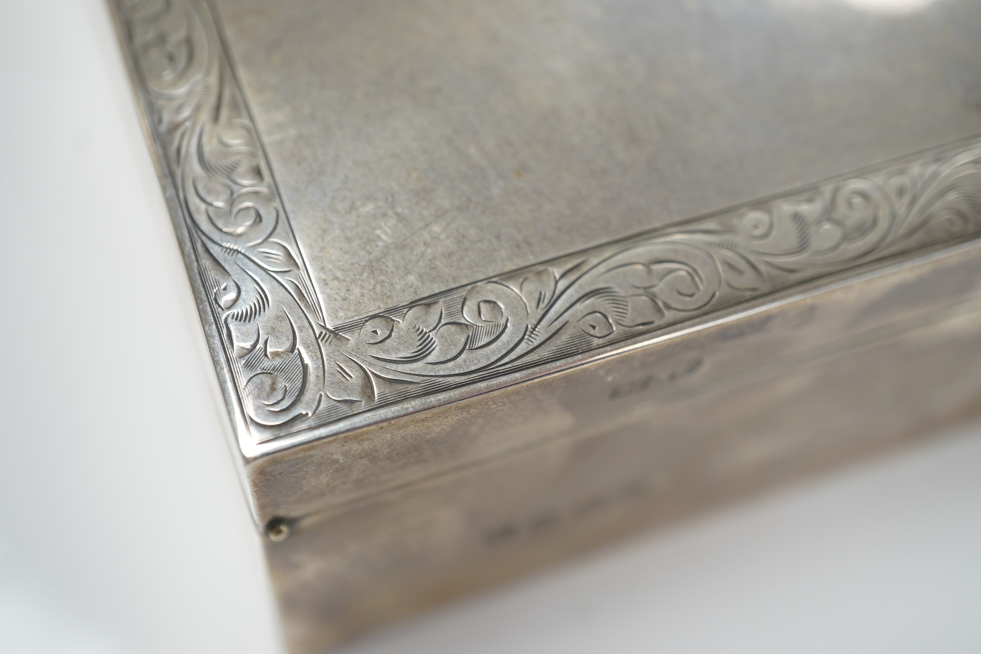 An Elizabeth II silver mounted rectangular cigarette box, with engraved inscription, C.S. Green & Co, Birmingham, 1975, 16.4cm. Condition - poor to fair